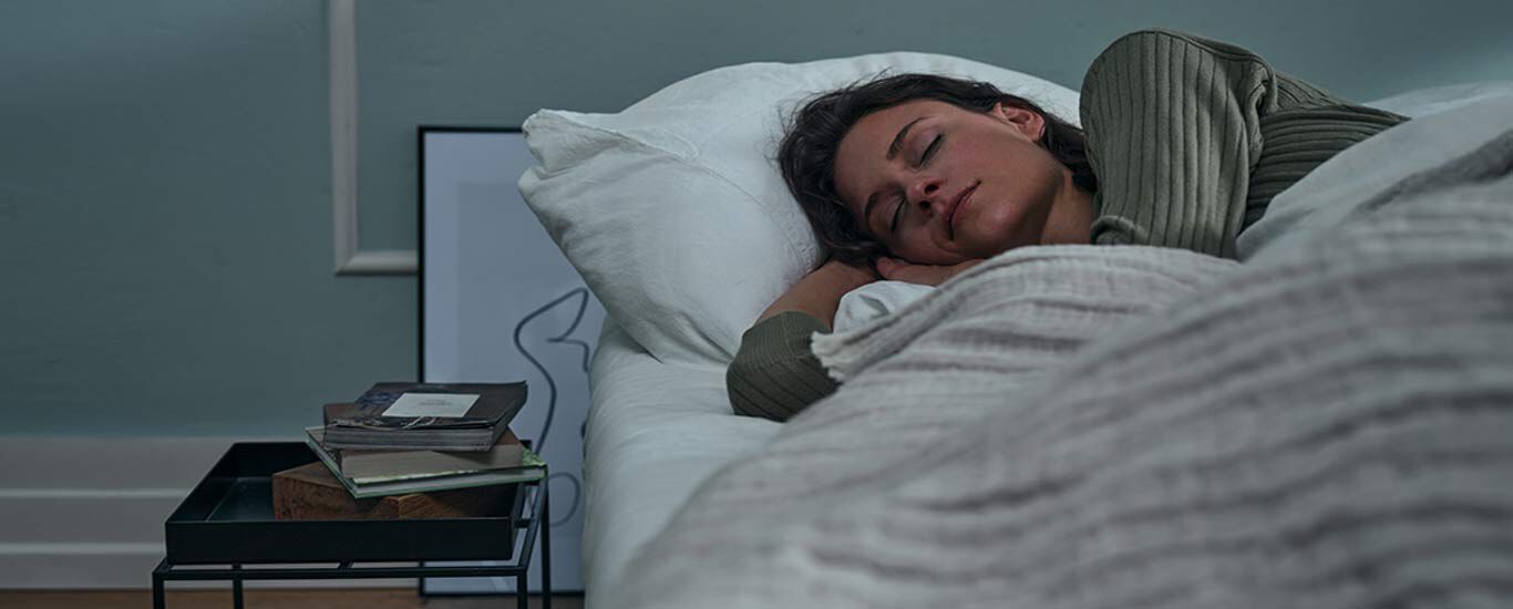 Une femme est allong&eacute;e dans son lit et dort.